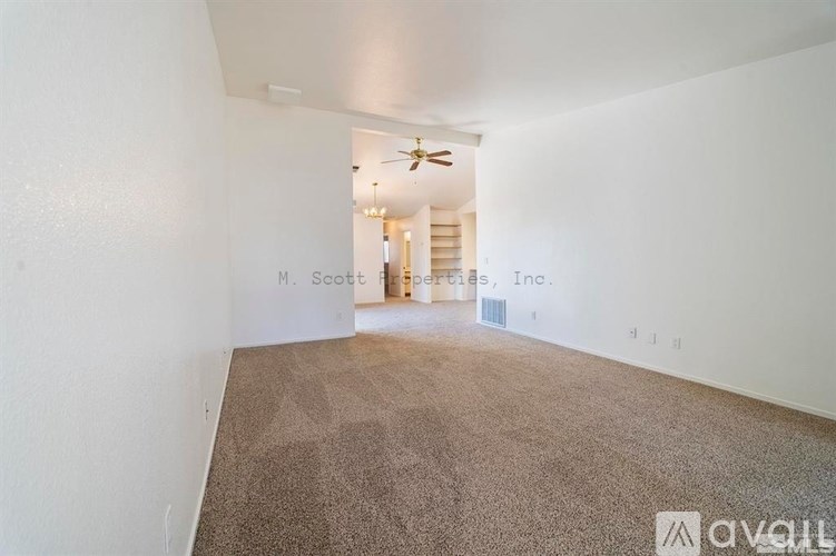 A room with a carpeted floor and a ceiling fan.