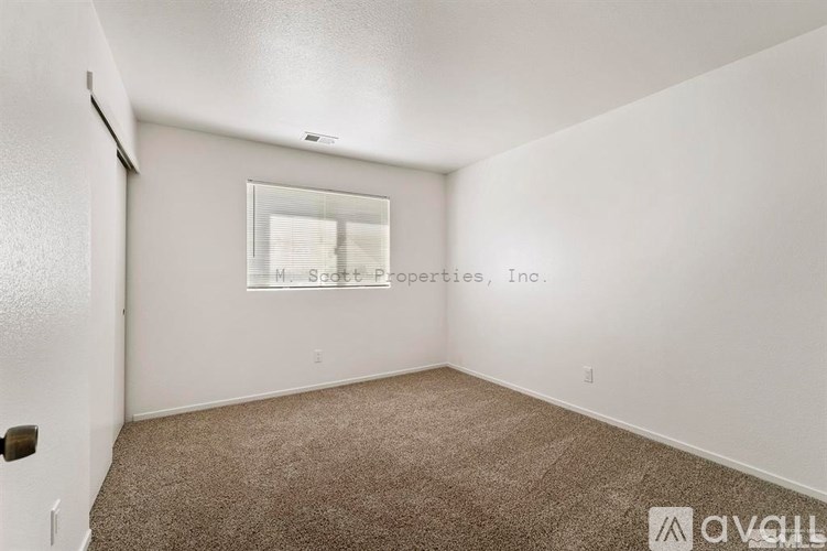 A room with a carpeted floor and a window showing a view of a building outside.