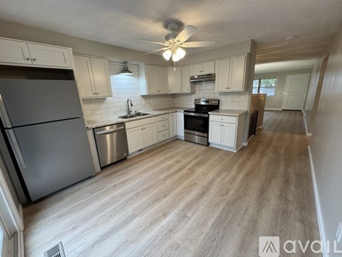 A kitchen with white cabinets and a wooden floor.