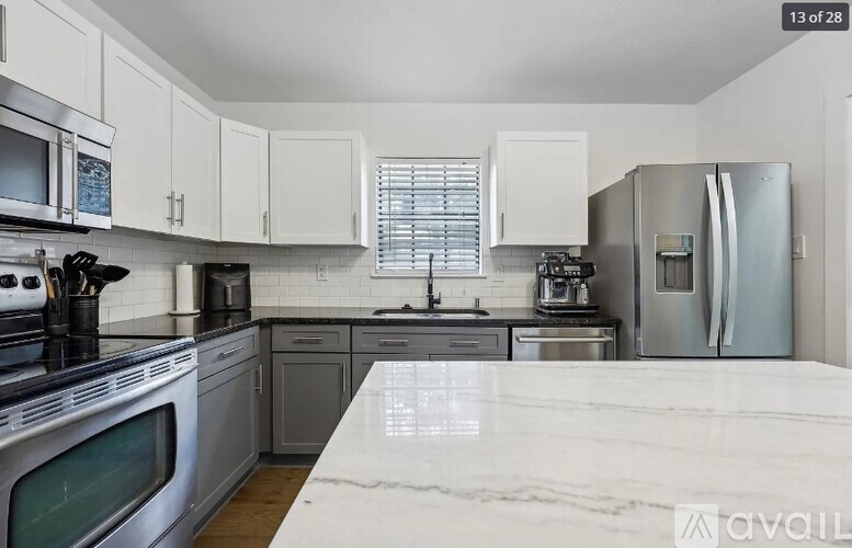 A kitchen with white cabinets and a marble countertop.