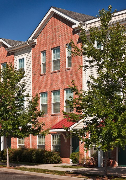 a red brick apartment building with white siding and trees