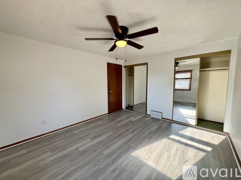 A room with a ceiling fan and wooden flooring.