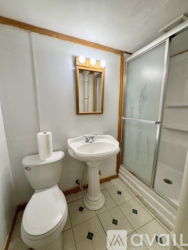 A white toilet and sink in a bathroom with a mirror above the sink.
