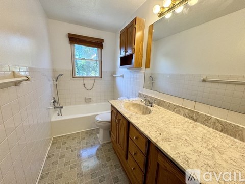 A bathroom with a toilet, sink, and a window.