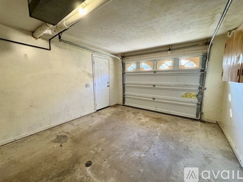 A spacious garage with a white door and a window with bars.