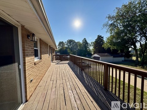 A wooden deck with a railing and a sunny sky in the background.