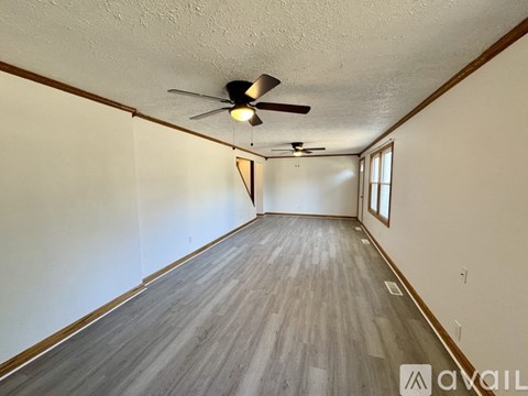 A room with a ceiling fan and wooden flooring.
