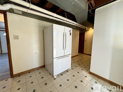 A white fridge in a room with tiled floors and white walls.