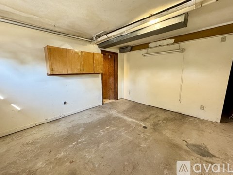 A room with a wooden door and a white wall with a brown cabinet on top.