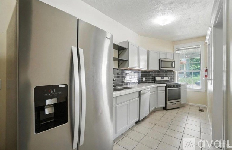A kitchen with a stainless steel refrigerator and white cabinets.