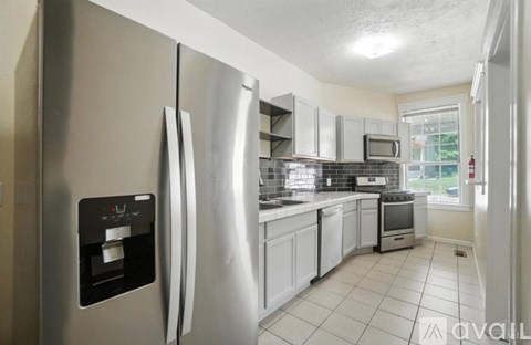 A kitchen with a stainless steel refrigerator and white cabinets.