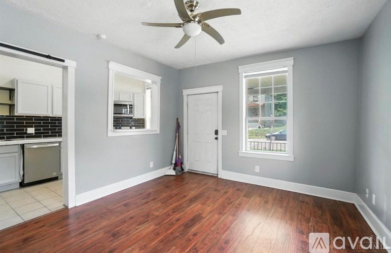 A room with a ceiling fan and wooden floors.