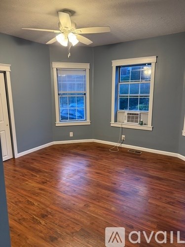 A room with wooden floors and two windows.