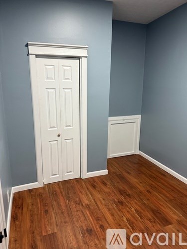 A room with a white door and wooden floor.