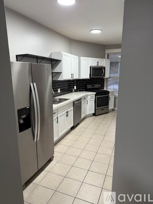 A kitchen with white cabinets and a stainless steel refrigerator.