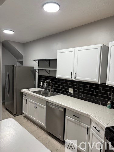A kitchen with white cabinets and a black backsplash.