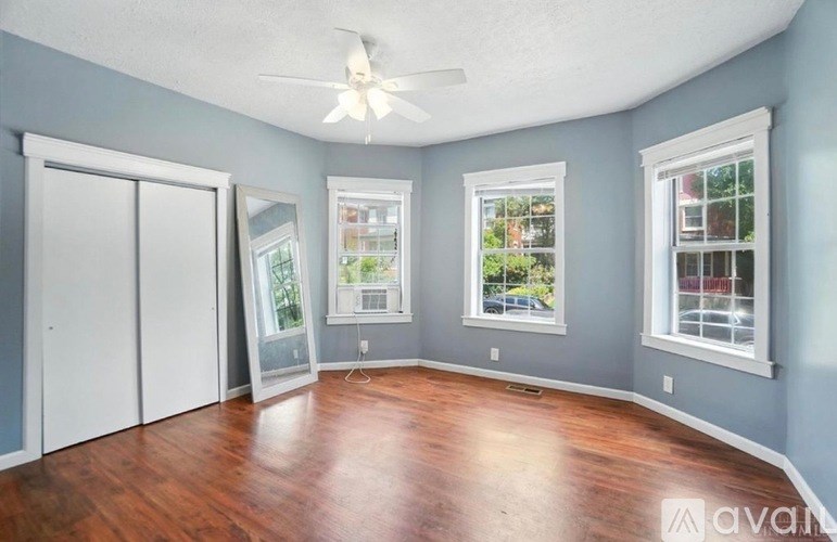 A room with a ceiling fan and three windows.