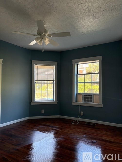 A white house with a tower-like structure on the roof is surrounded by other houses.