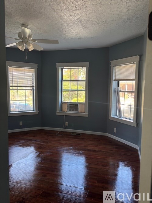 A room with a ceiling fan and two windows.