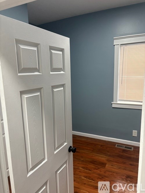 A white door with a black handle is in a room with blue walls.