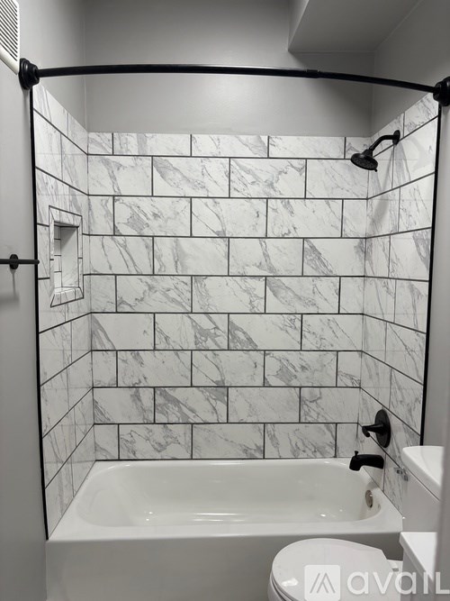 A white bathroom with a marble tile shower.