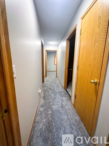 A hallway with a carpeted floor and wooden doors on either side.