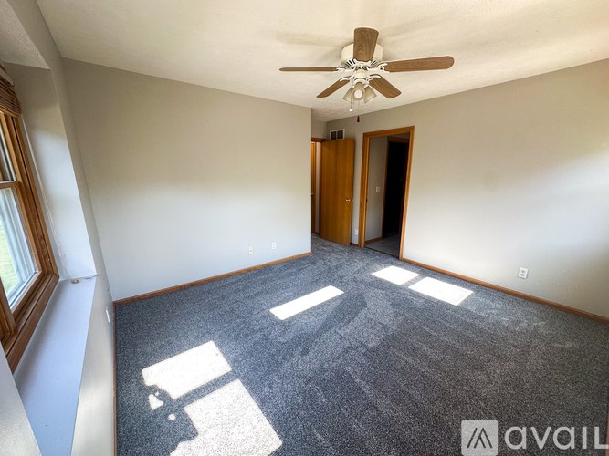 A room with a ceiling fan and a carpeted floor.