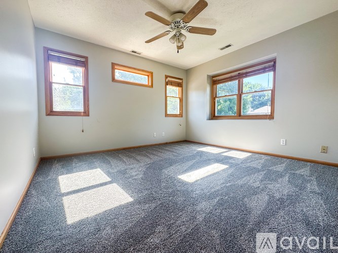 A room with a ceiling fan and three windows.
