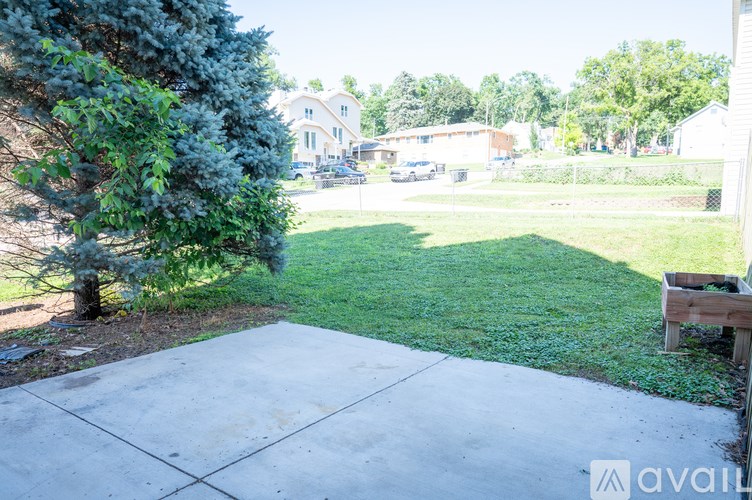 A backyard with a concrete patio and a tree.