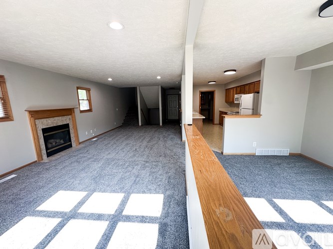 A large empty room with a fireplace and a carpeted floor.