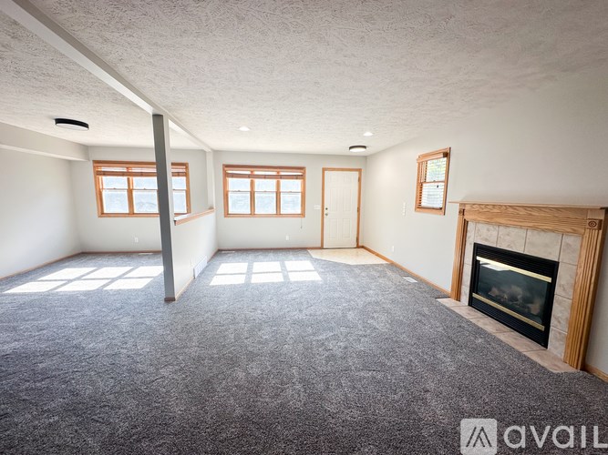 A living room with a fireplace and a grey carpet.