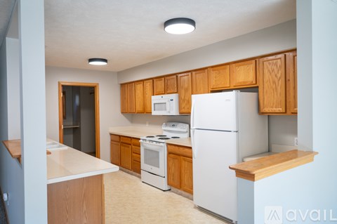 A kitchen with white appliances and wooden cabinets.