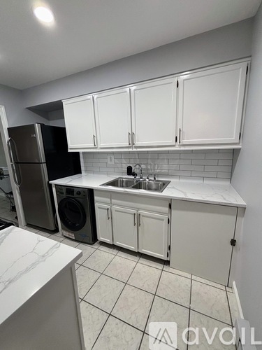 A kitchen with white cabinets and a marble countertop.