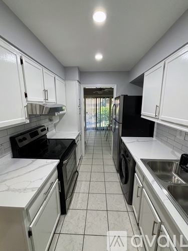 A kitchen with white cabinets and black appliances.