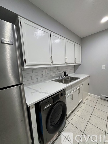 A kitchen with a stainless steel refrigerator and white cabinets.