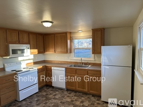 A kitchen with wooden cabinets and a white refrigerator is on the market with Shelby Real Estate Group.