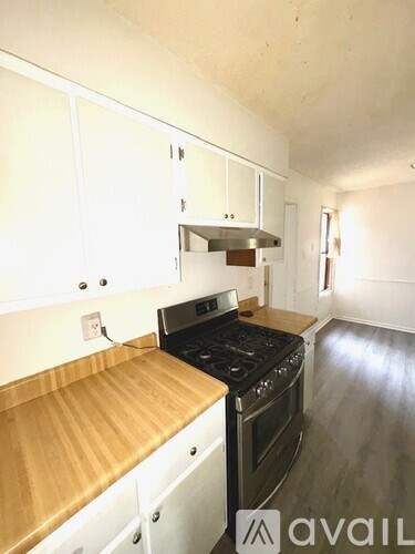 A kitchen with white cabinets and a wooden countertop.