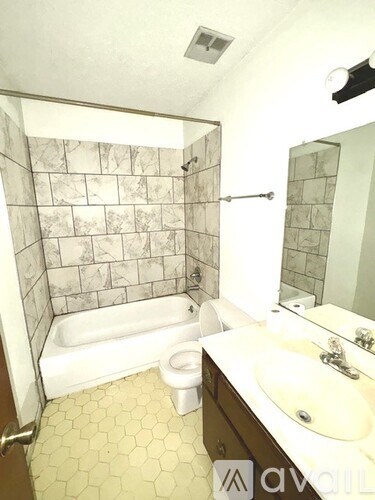 A bathroom with a marble tile shower, white bathtub, and a sink with a mirror.