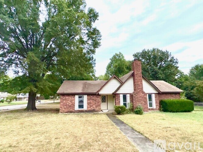 A house with a brick chimney and a tree in front.