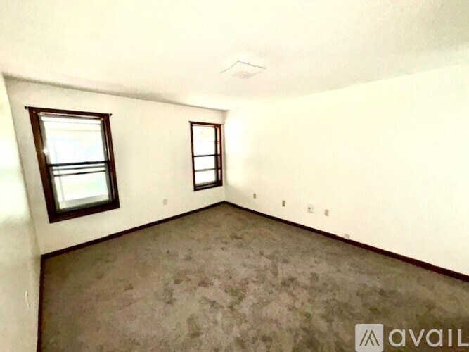 A room with two windows and carpeted floor.