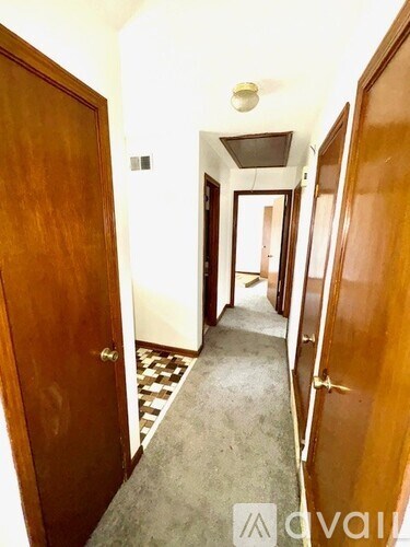 A hallway with a checkered floor and wooden doors.