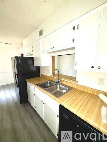 A kitchen with black fridge and white cabinets.