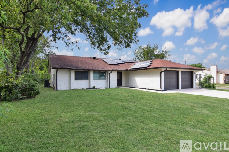 A house with a brown roof and white walls is surrounded by a green lawn.