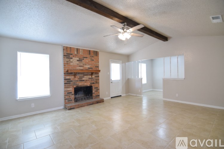 A spacious living room with a fireplace and a ceiling fan.