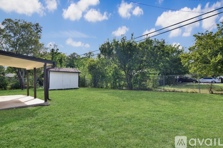 A backyard with a white shed and a fence.