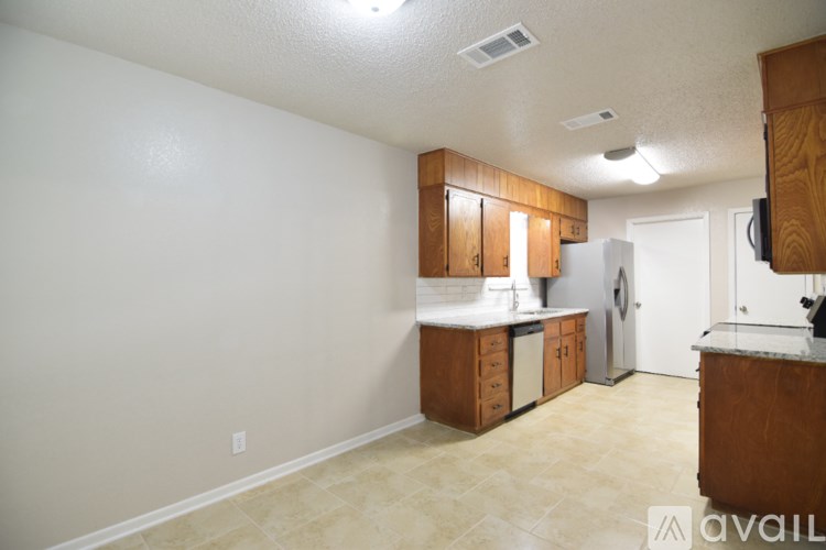 A kitchen with white walls and wooden cabinets.