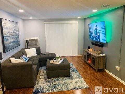 A living room with a grey couch, a blue rug, and a painting on the wall.