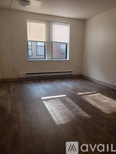 A room with wooden floors and a window with blinds.