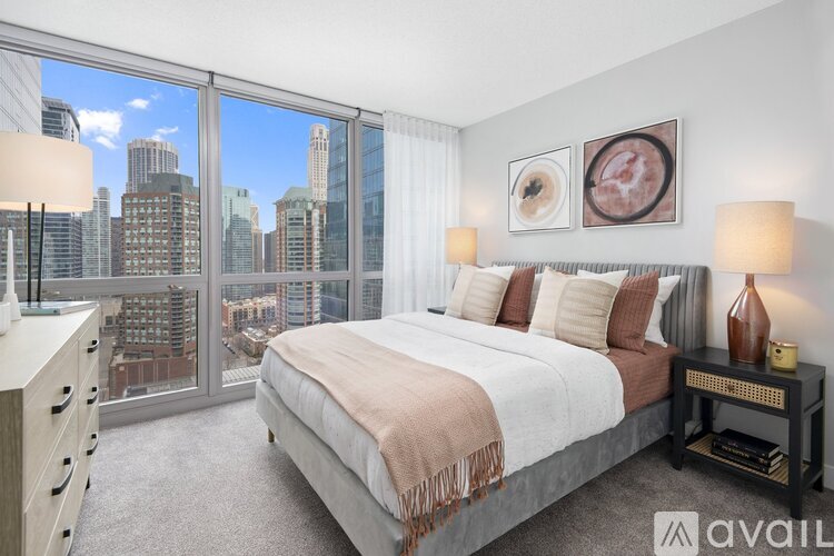 A bedroom with a large bed and a city view through the window.