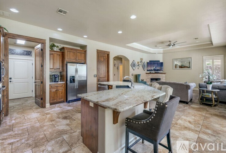 A kitchen with a marble island and a dining table with chairs.